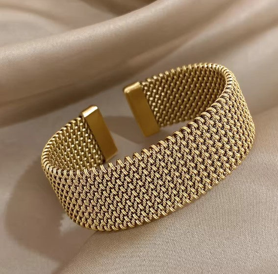 Bredt guld mesh manchetarmbånd til kvinder med elegant åbent design. Et moderne damearmbånd.