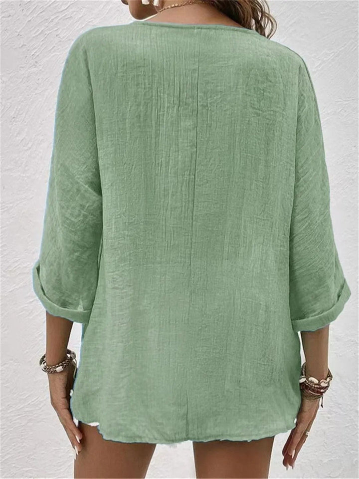 Sidebillede af oversized damebluse med V-hals og trekvart ærmer. Afslappet pasform i bomuld.