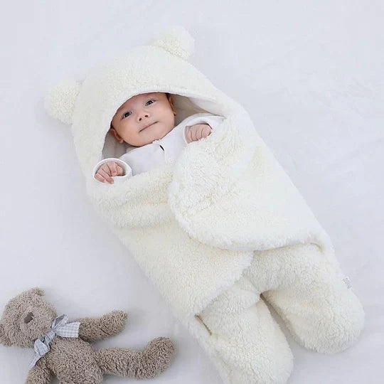 Blødt CuddleCloud baby svøbetæppe i behageligt stof, der giver tryghed og hygge til nyfødte og småbørn.