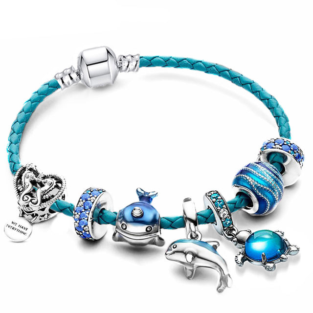 Dame charm armbånd med blå havtema perler og glitrende delfin vedhæng, et unikt sommer smykke.