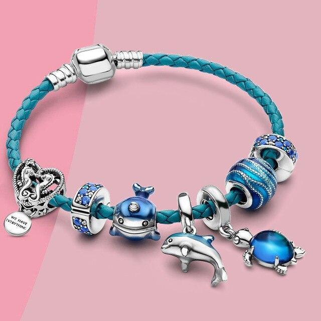 Smukt damearmbånd med turkise havperler og charmerende delfin vedhæng, perfekt til strandstil.