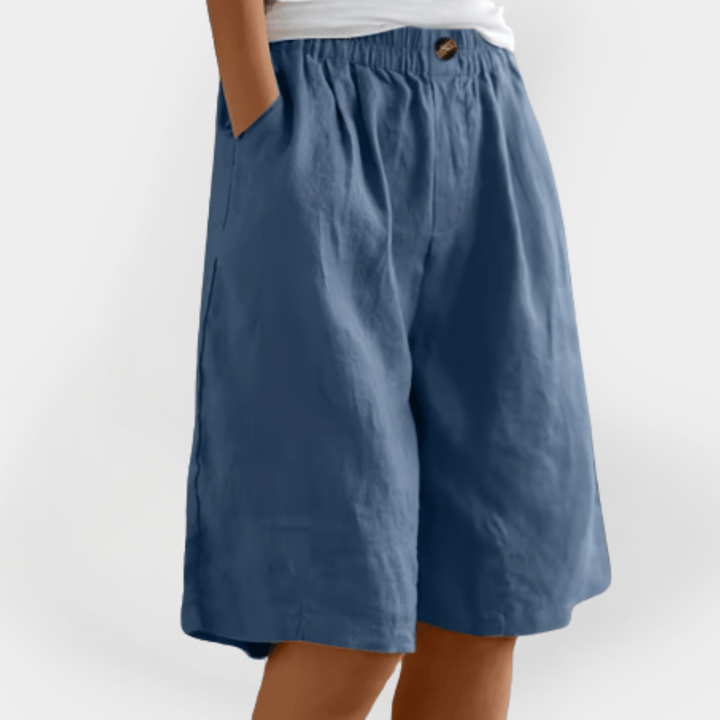 Model sidder afslappet i dame sommer shorts, fremhævende bevægelsesfrihed og komfort til fritidsbrug.