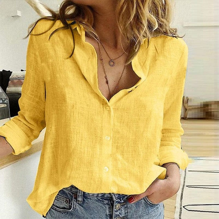 Nærbillede af knapdetaljer og V-hals på en elegant damebluse. Fremhæver kvalitetsdesign og moderne stil.
