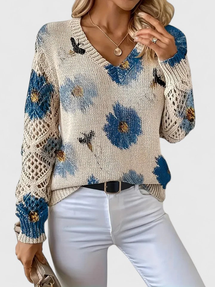 Model bærer en blomstret damebluse med V-hals og lange blondeærmer. Hverdag og fest.
