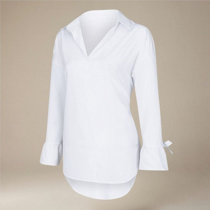 Nærbillede af den elegante sløjfe på den hvide langærmede damebluse, der tilføjer et chic touch til looket.