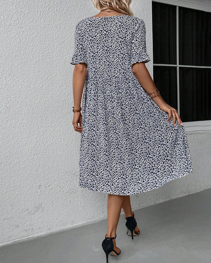 Feminin blomstret midikjole med smukt mønster, ideel til forårsmode og sommerdage.