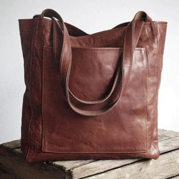 Kvinde bærer elegant brun læder skuldertaske, ideel til arbejde eller en stilfuld udflugt. Modetilbehør.