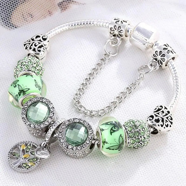 Elegant dame charm armbånd med grønne glasperler og skinnende sølvdetaljer, perfekt som gave.