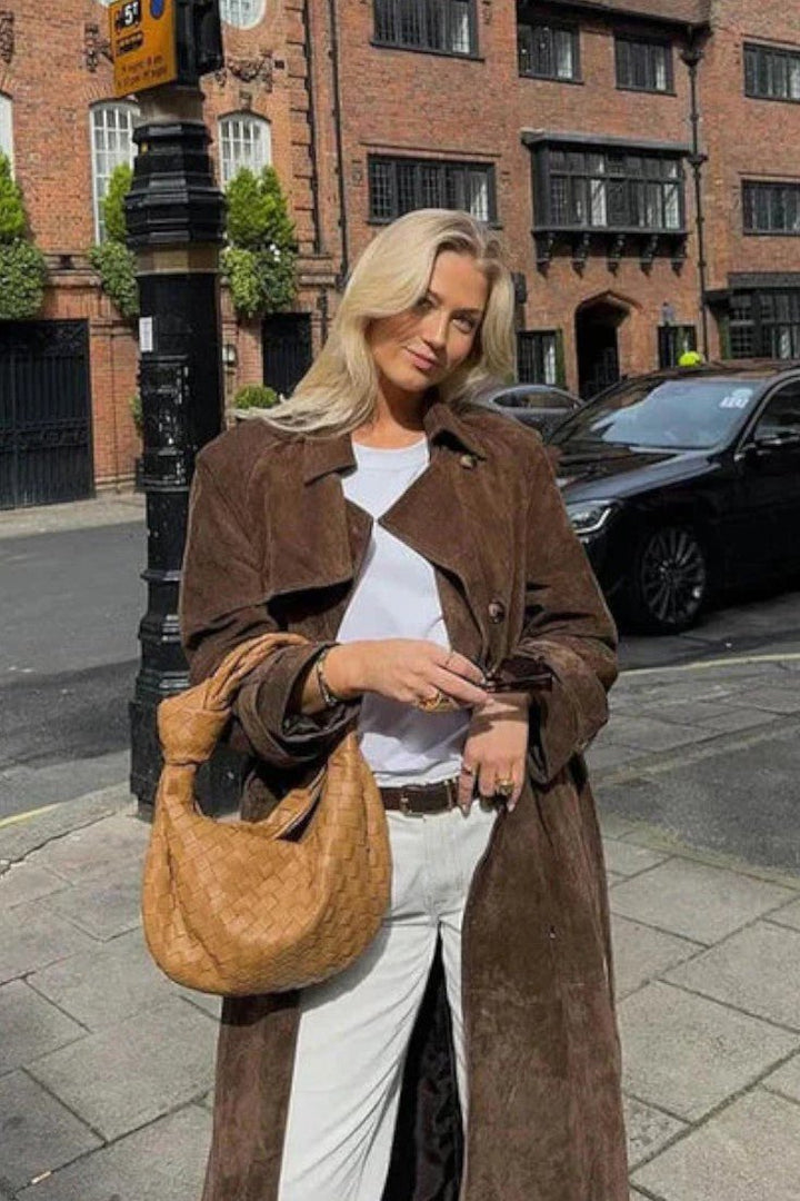 Tidløs beige trenchcoat med dobbeltradet knaplukning og reverskrave. Elegant og stilfuld damejakke.