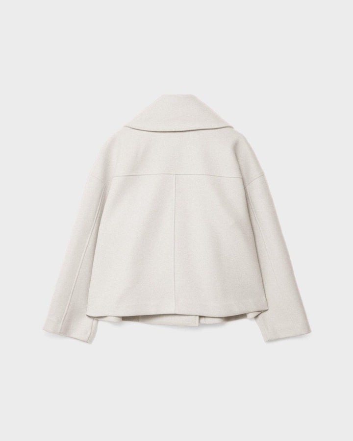 Nærbillede af stoffet på en eksklusiv dobbeltbrystet damejakke, der viser kvalitet og håndværk.