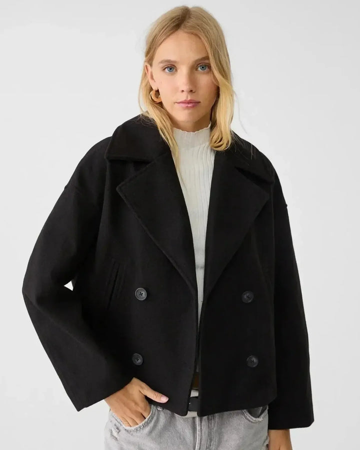 Rygvisning af en klassisk kort damejakke med dobbeltbrystet design. Elegant og moderne stil med kvalitet.