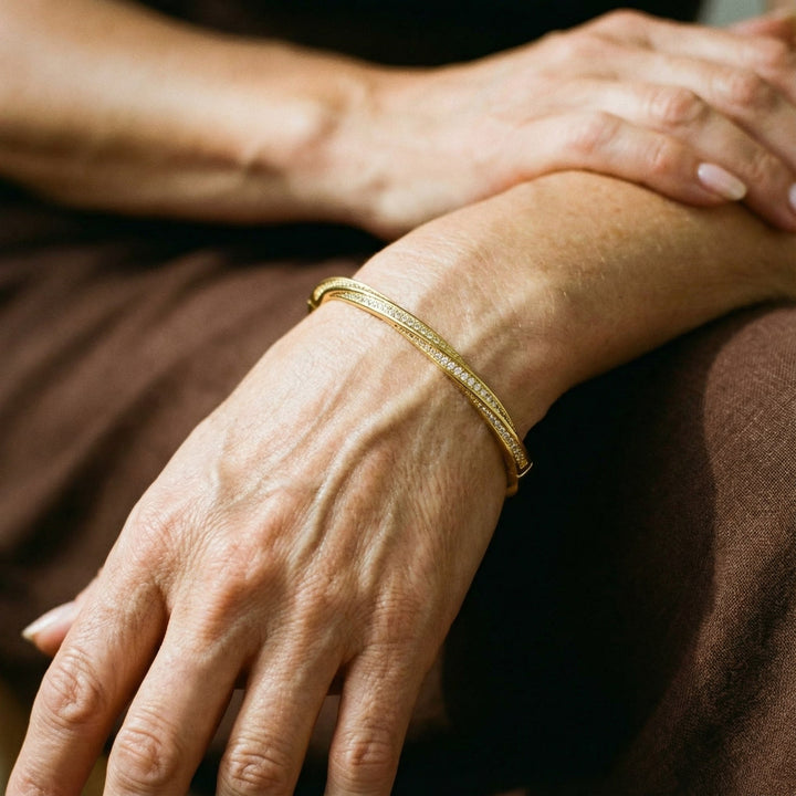 Luksuriøst krystal armbånd i guld designet som en bangle. Ideelt damearmbånd for glamour og festlook.