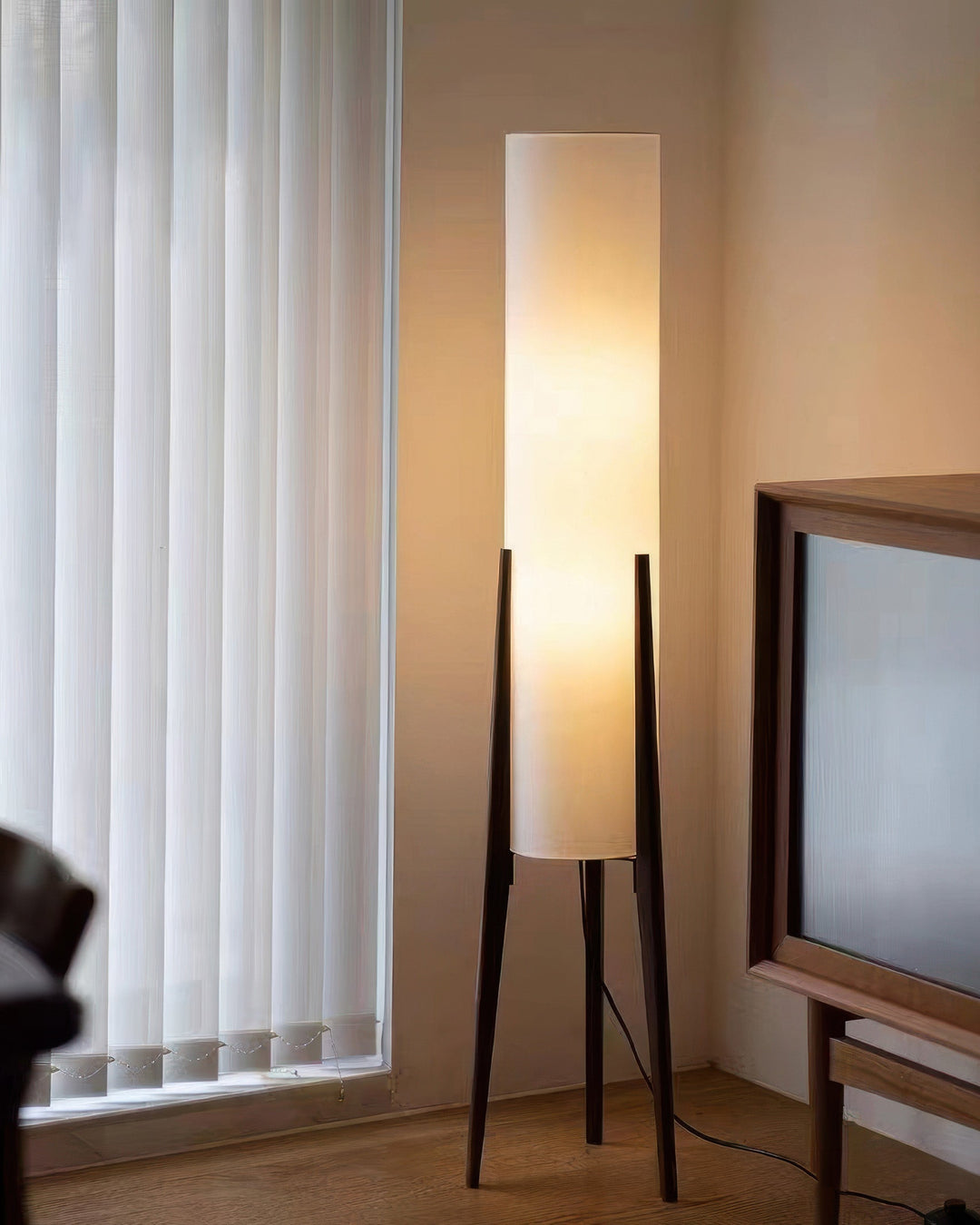 "Elegant gulvlampe i valnød med nordisk retrodesign, solid træbase og blød stofskærm, skaber hyggelig belysning."
