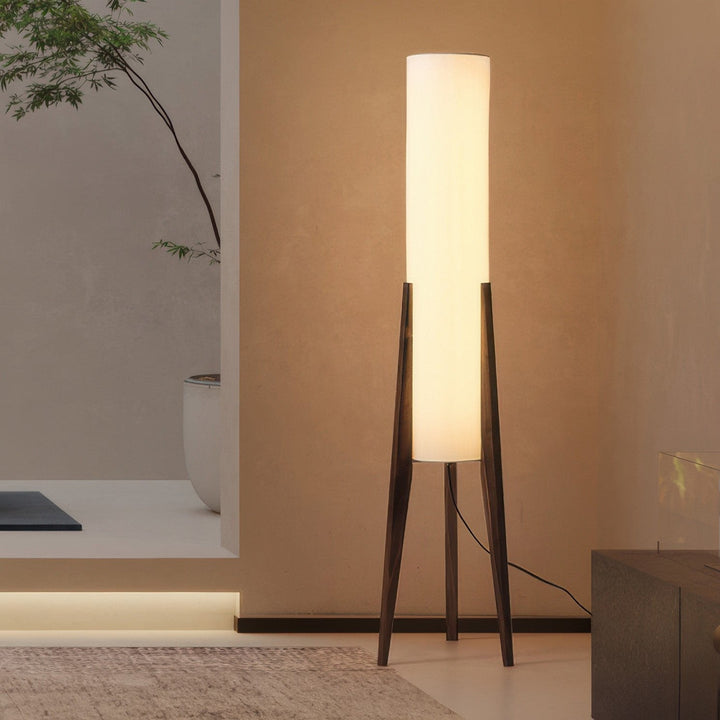 "Elegant gulvlampe i valnød med nordisk retrodesign, solid træbase og blød stofskærm, skaber hyggelig belysning."