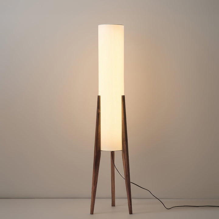 "Elegant gulvlampe i valnød med nordisk retrodesign, solid træbase og blød stofskærm, skaber hyggelig belysning."