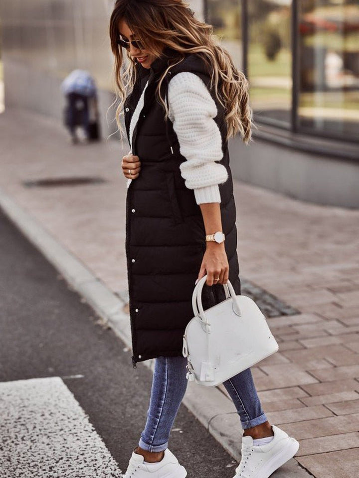 "Elegant kvindevest i quiltet design, knælang og ærmeløs, ideel til vinter, med lynlås og sidelommer for stil og komfort."
