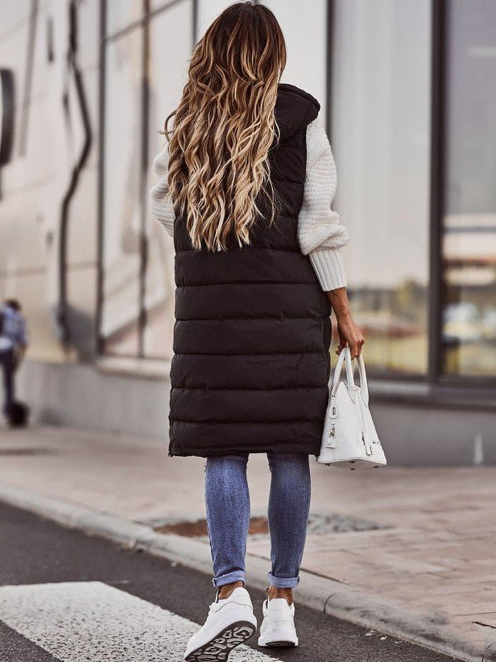 "Elegant kvindevest i quiltet design, knælang og ærmeløs, ideel til vinter, med lynlås og sidelommer for stil og komfort."