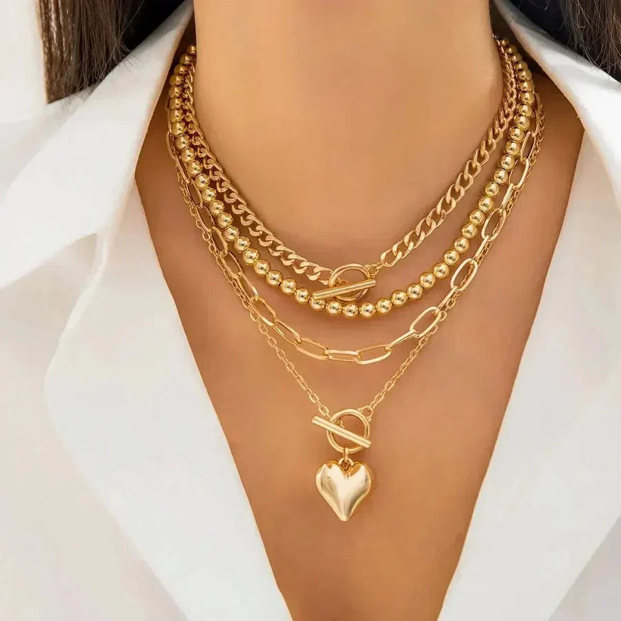 Elegant lagdelt damehalskæde med romantisk hjertevedhæng i guld og sølv. Trendy smykke til kvinder.