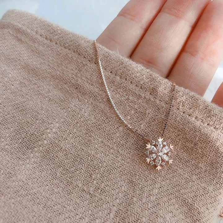 Feminint snefnug smykke: Damehalskæde i rosa guld og sølv med glitrende krystal detaljer. Vinterinspireret design.