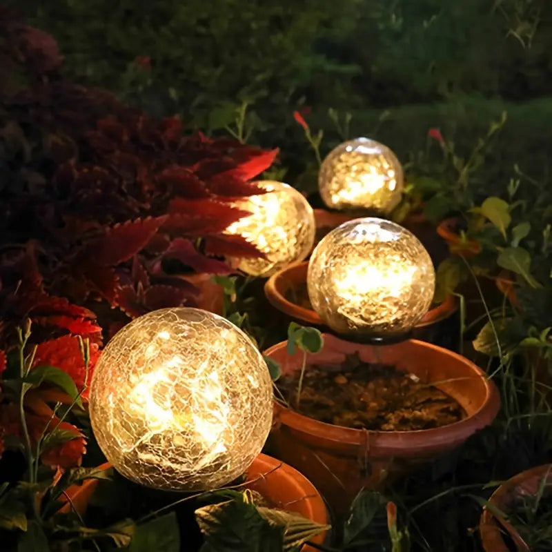 Krakeleret solcelle kuglelampe placeret i græsplænen, lyser en hyggelig gangsti op i aftenmørket.