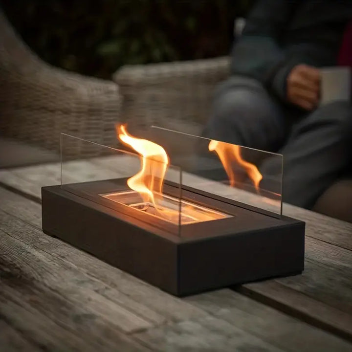 "Elegant sort bioethanol udendørspejs i rustfrit stål, dimensioner 35x18x14 cm, skaber hygge og varme i haven."
