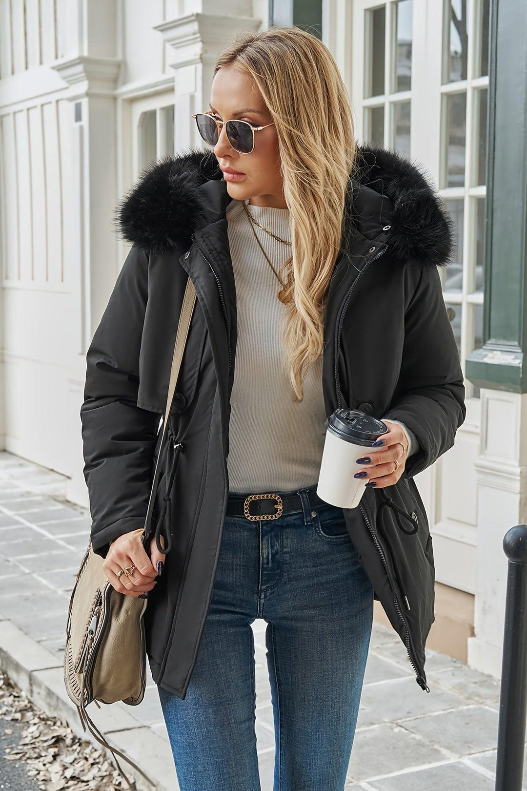 Kvinde poserer i stilfuld sort vinterjakke med faux fur hætte. Elegant og varm kvindejakke til vinter.