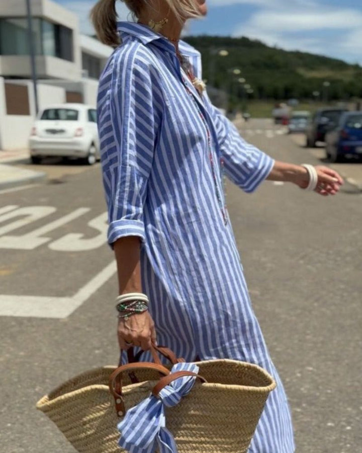Kvinde iført lang stribet skjortekjole, der viser dens alsidighed som elegant sommerkjole til både fest og hverdag.