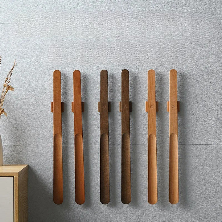 Elegant væghængt skohorn i lyst træ med magnetisk fæste, perfekt til entréen.