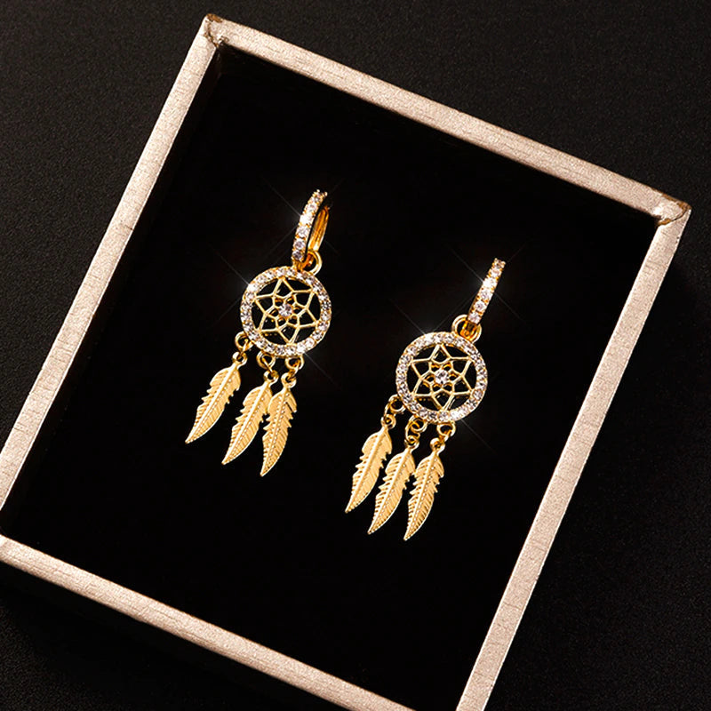 Elegante drømmefangerøreringe i 14K guld til kvinder. Unikt design med fjer og krystal detaljer.
