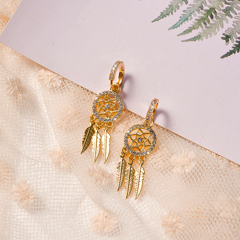 Dame øreringe i 14K guld med drømmefanger design. Luksuriøst smykke med krystal og fjer, perfekt gave.