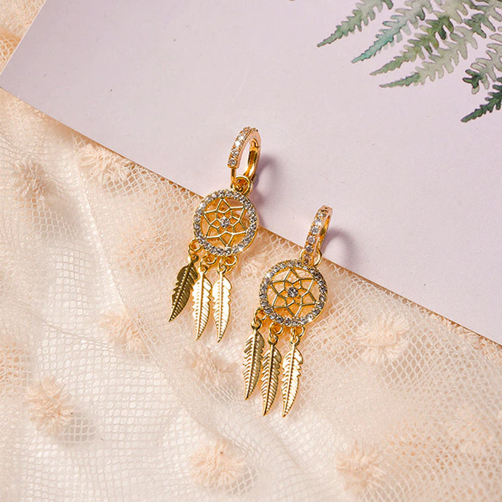 Dame øreringe i 14K guld med drømmefanger design. Luksuriøst smykke med krystal og fjer, perfekt gave.