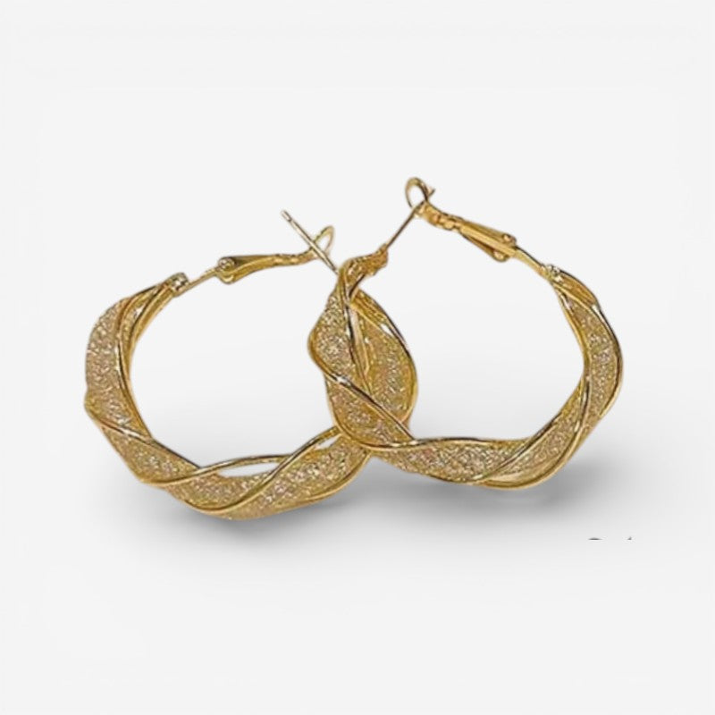 Elegante guld creoløreringe med snoet design til kvinder, perfekte som stilfuldt hverdags smykke.