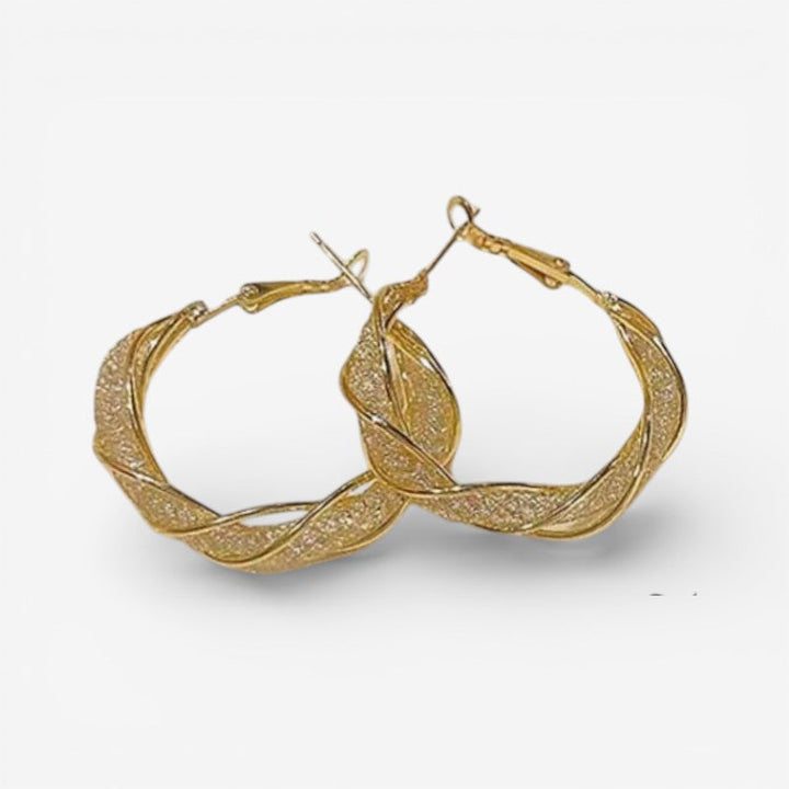 Elegante guld creoløreringe med snoet design til kvinder, perfekte som stilfuldt hverdags smykke.