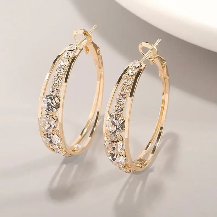 Elegante guld creoler til kvinder med funklende krystaller. Perfekte som festsmykker eller til hverdagsbrug.