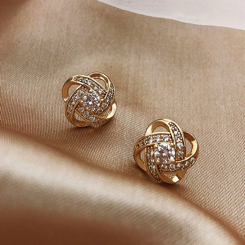 Elegante guld ørestikker til kvinder med funklende zirkonia sten og unikt flettet design.