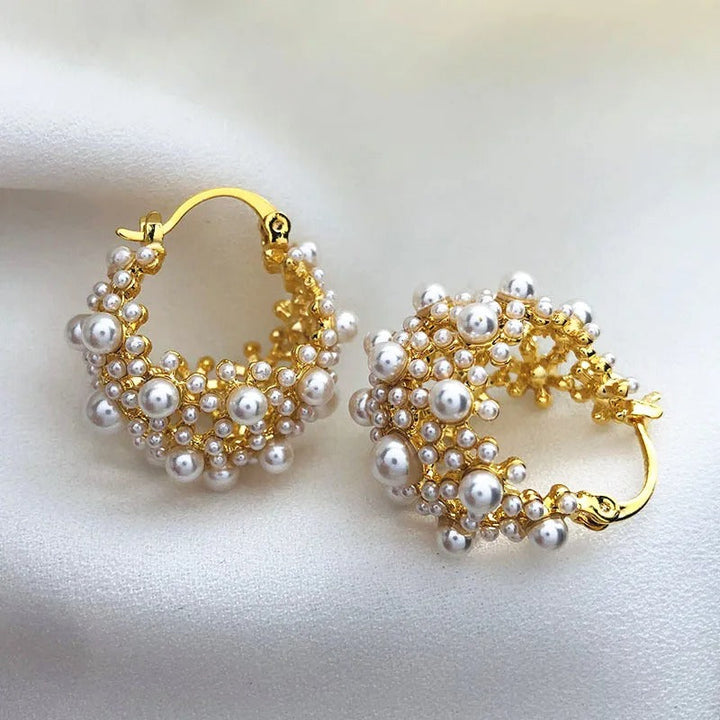 Elegante kvinders statement creoler i guld med skinnende hvide perler. Perfekte modeøreringe til fest eller gave.