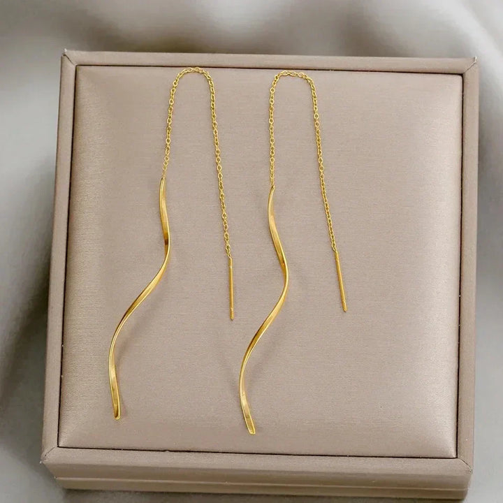 Iøjnefaldende lange bølgede øreringe til kvinder. Et elegant statement-smykke i guld.