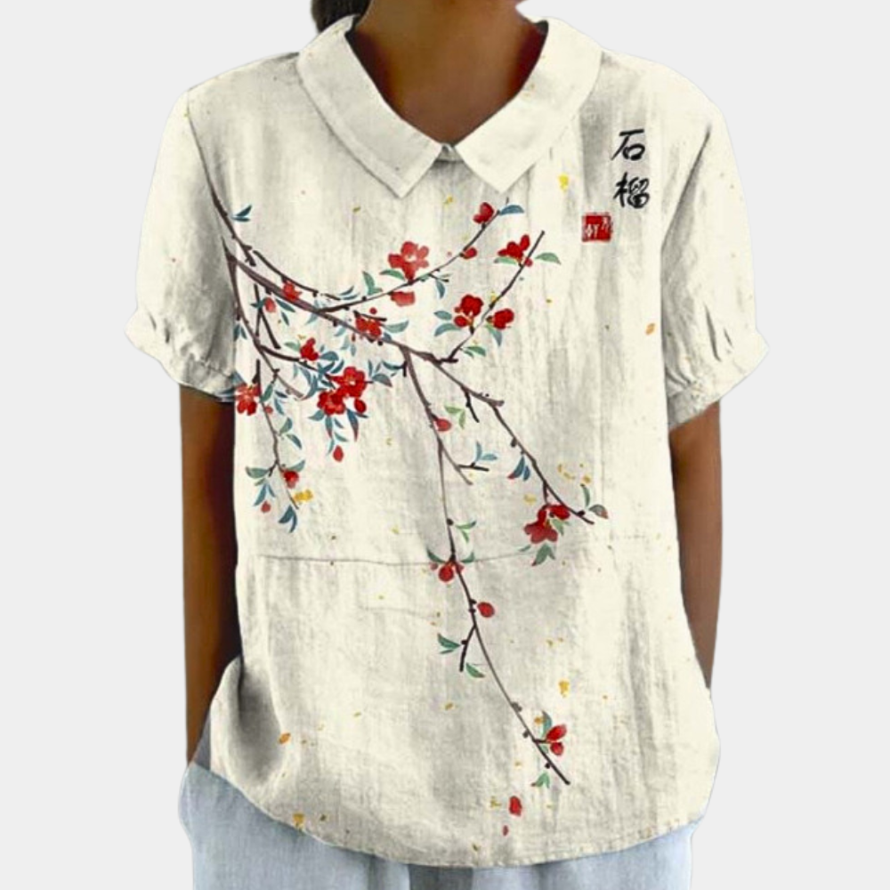 Farverig damebluse med smukt blomstermønster, korte ærmer og rund hals, perfekt til et stilfuldt hverdagslook.