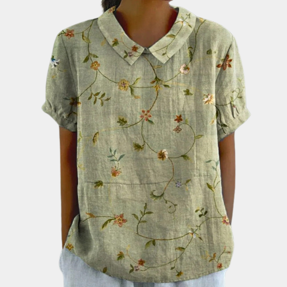 Levende damebluse med blomstermønster og rund krave, ideel til sommer. En stilfuld opgradering til enhver garderobe.
