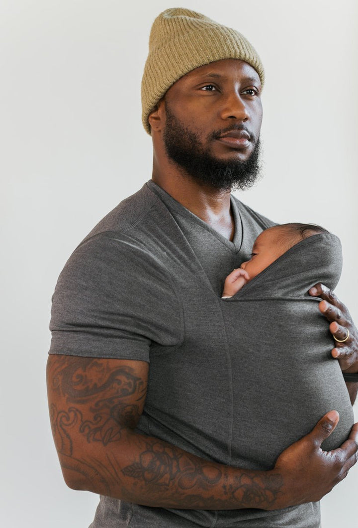 Nærbillede af blød bære-t-shirt med baby tæt ind til forælder. Fremmer nærhed og tryghed.