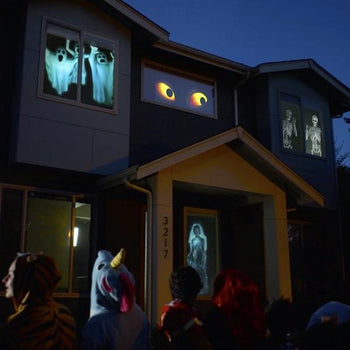 Børn kigger forskrækket på spøgelser og gys projiceret på vinduet med Halloween vinduesprojektor til fest.