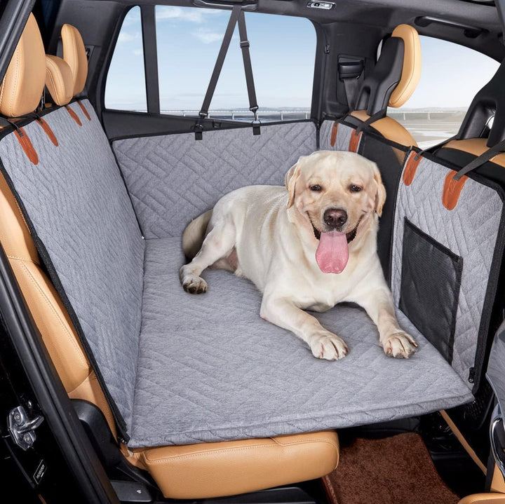 Glad hund slapper af på et sort hundesædebetræk i bilen, der holder sædet rent og beskyttet.
