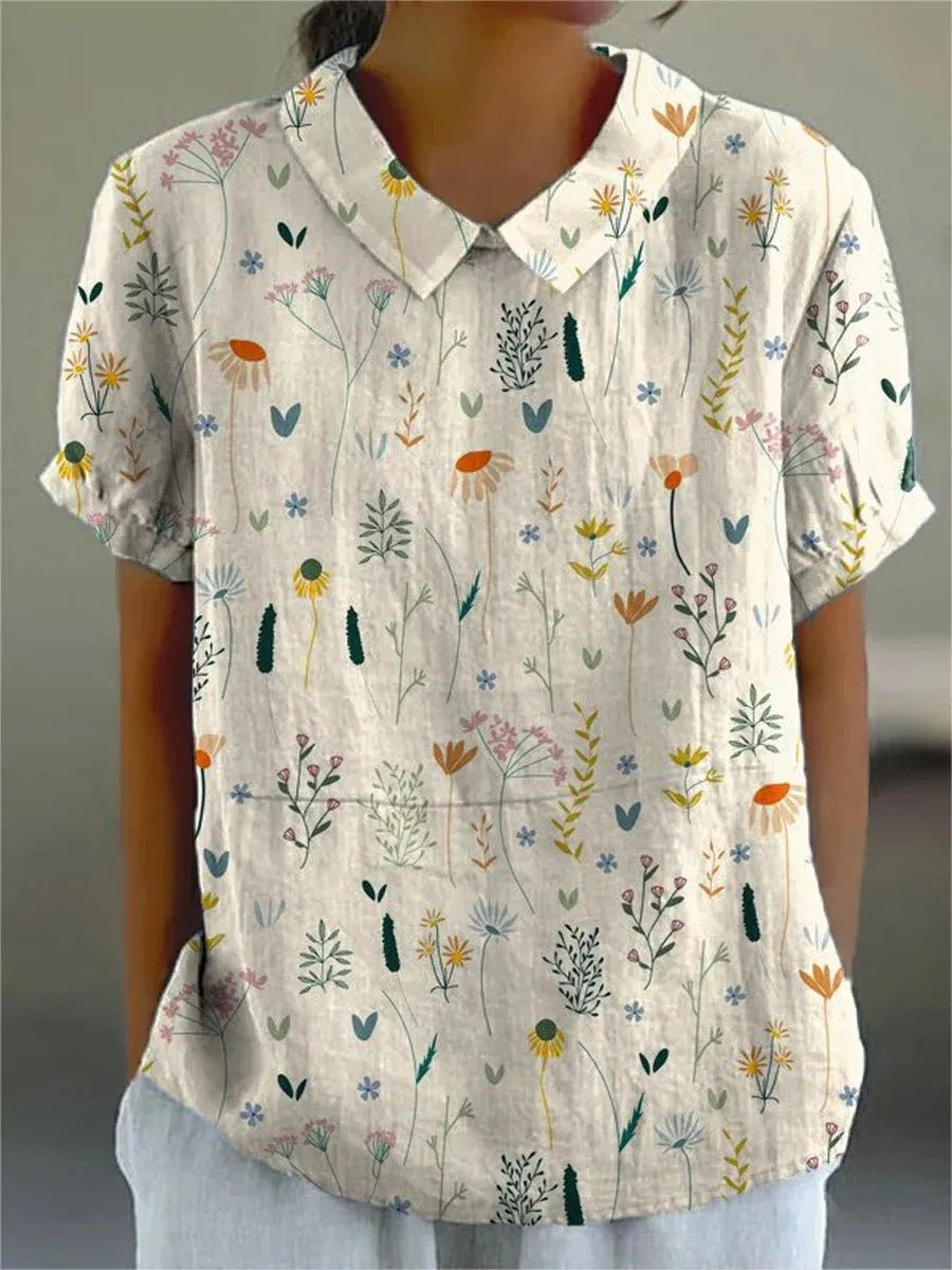 Hvid dame polo skjorte med elegant blomstermønster og løs pasform. Komfortabel casual top perfekt til sommeren.