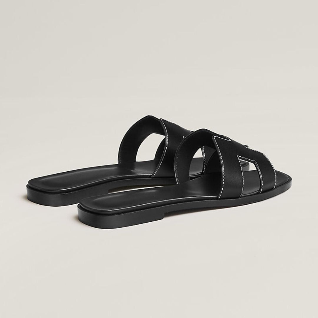 Elegante damesandaler med perforerede remme og justerbare spænder, fås i hvid, sort og brun.