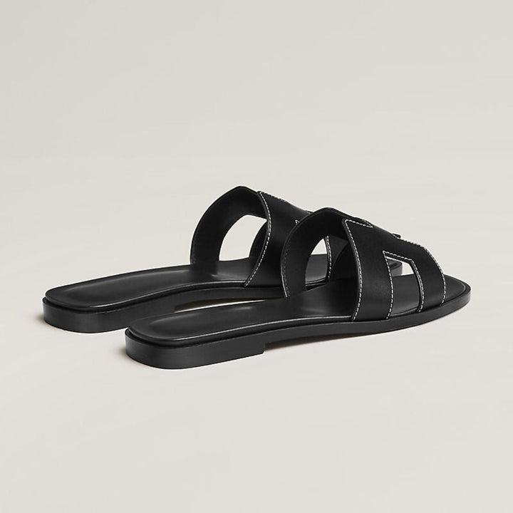 Elegante damesandaler med perforerede remme og justerbare spænder, fås i hvid, sort og brun.