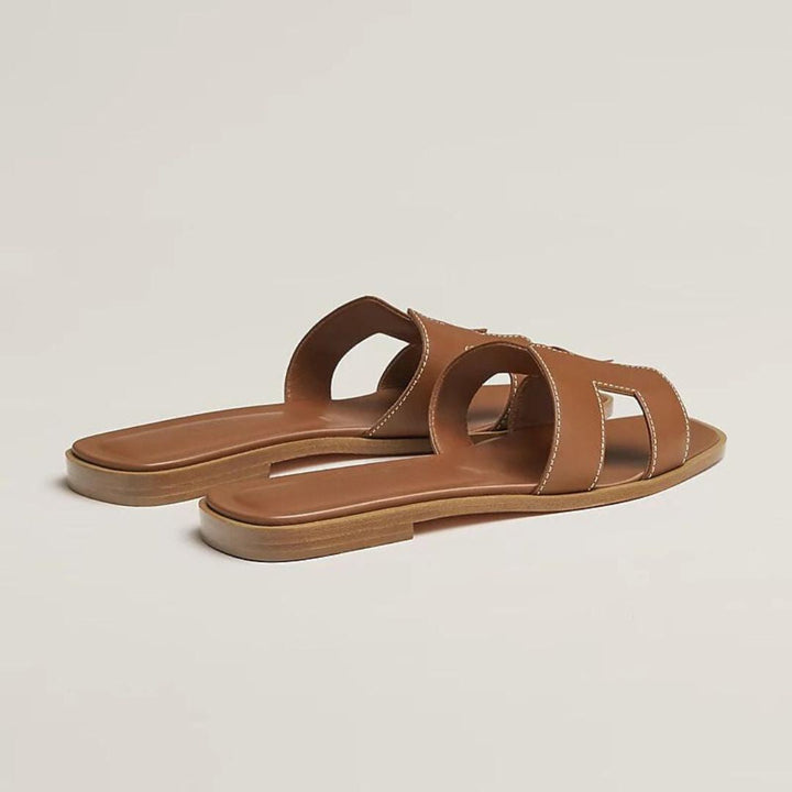 Brune flade damesandaler med elegant perforering, justerbare stropper. Perfekt til sommerens varme dage.