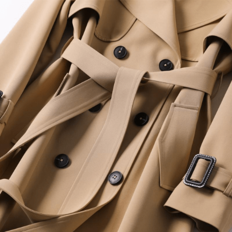 Tidløs dame trenchcoat med bælte og revers. Ideel som lang, elegant frakke til både forår og efterår.