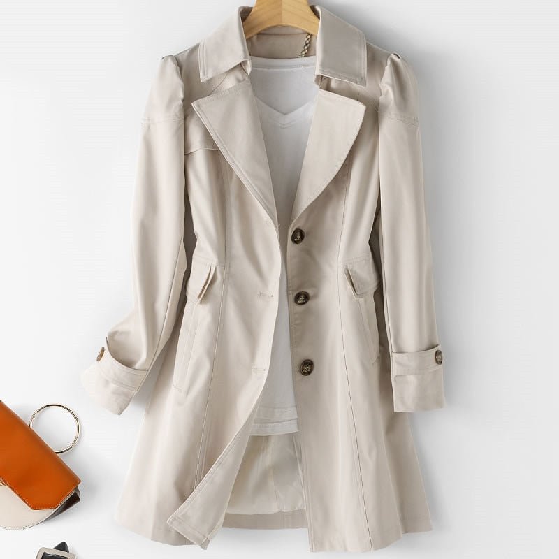 Kvindelig trenchcoat i beige med klassisk snit, knaplukning, letvægts og vandafvisende materiale. Set forfra mod baggrund.
