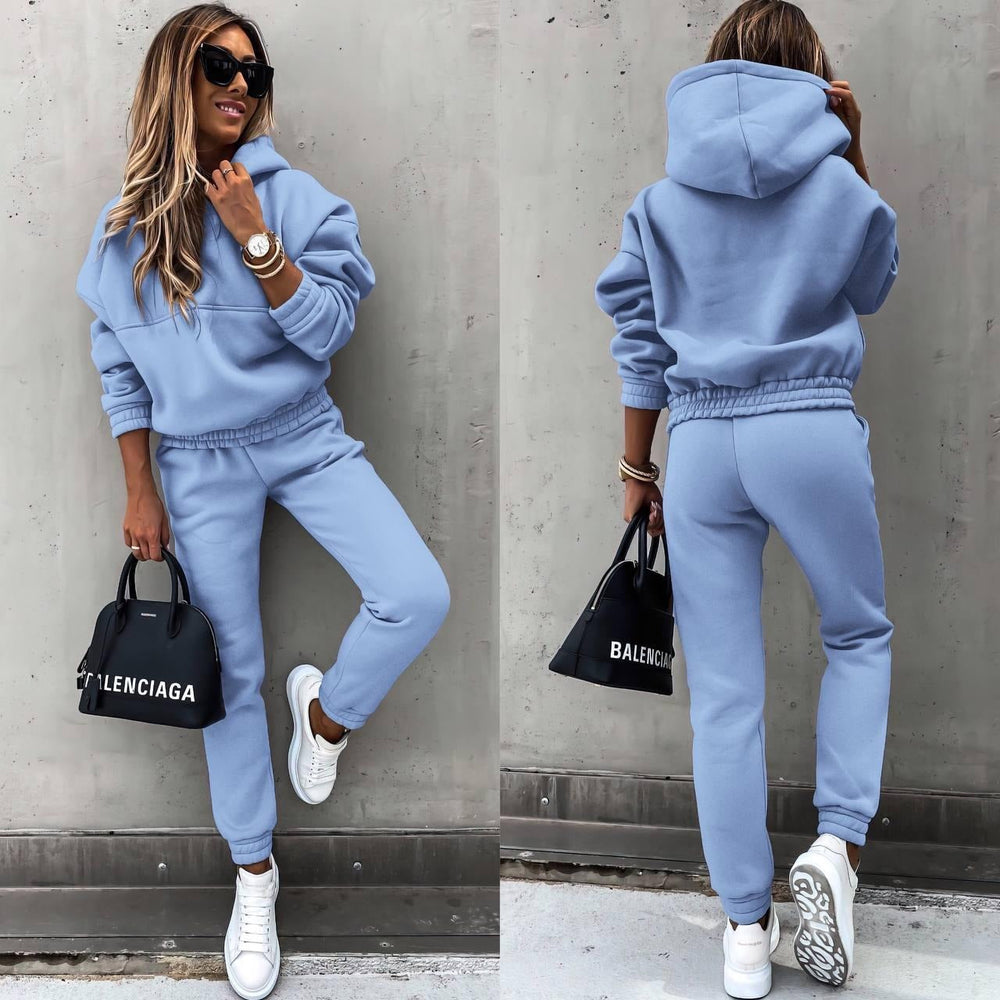 Model iført kvinders sporty todelt sæt med sweatshirt og matchende joggingbukser i blødt stof.