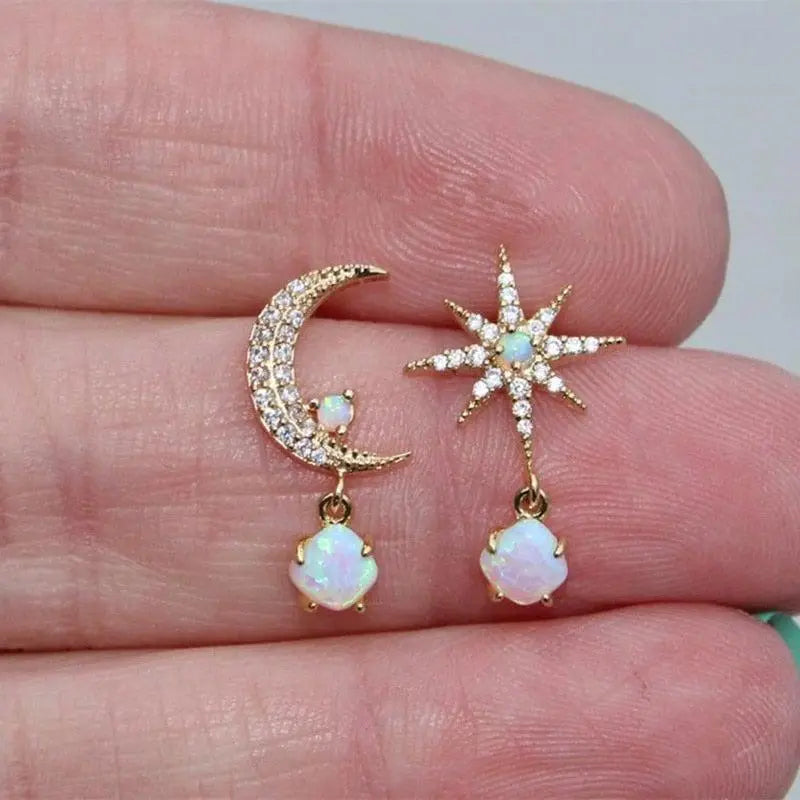 Detaljeret billede af kvinders dingle øreringe: gylden måne og stjerne med iriserende opal sten.
